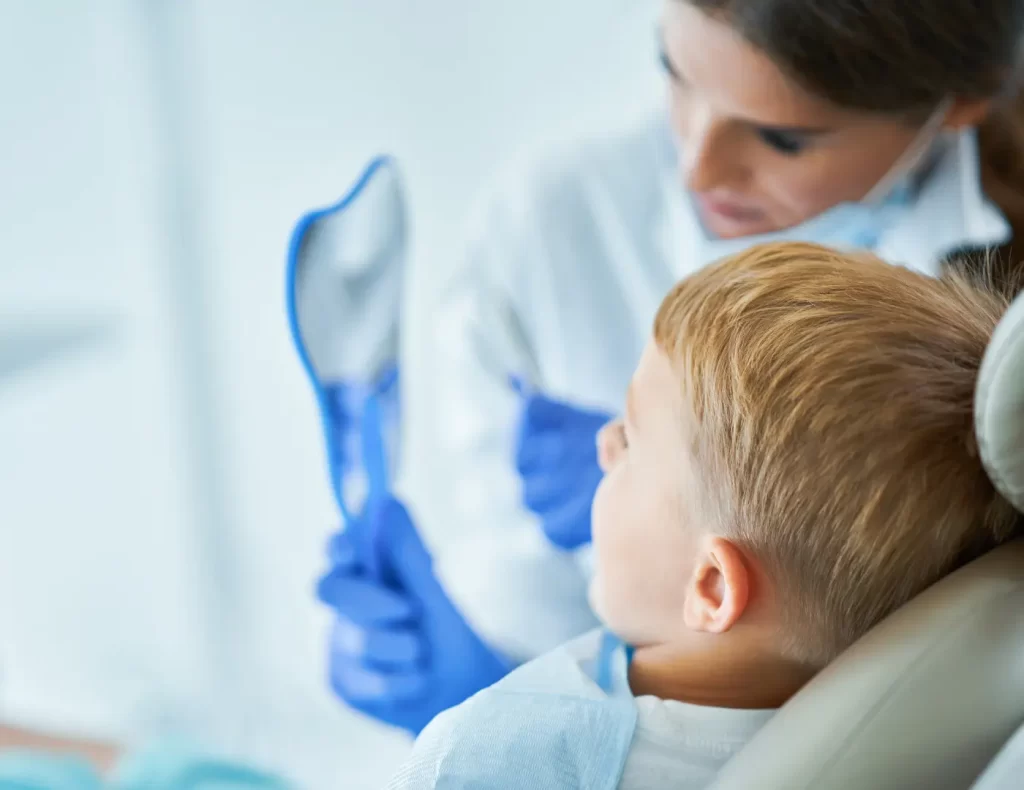 Odontopediatra mostrando su reflejo a un paciente infantil