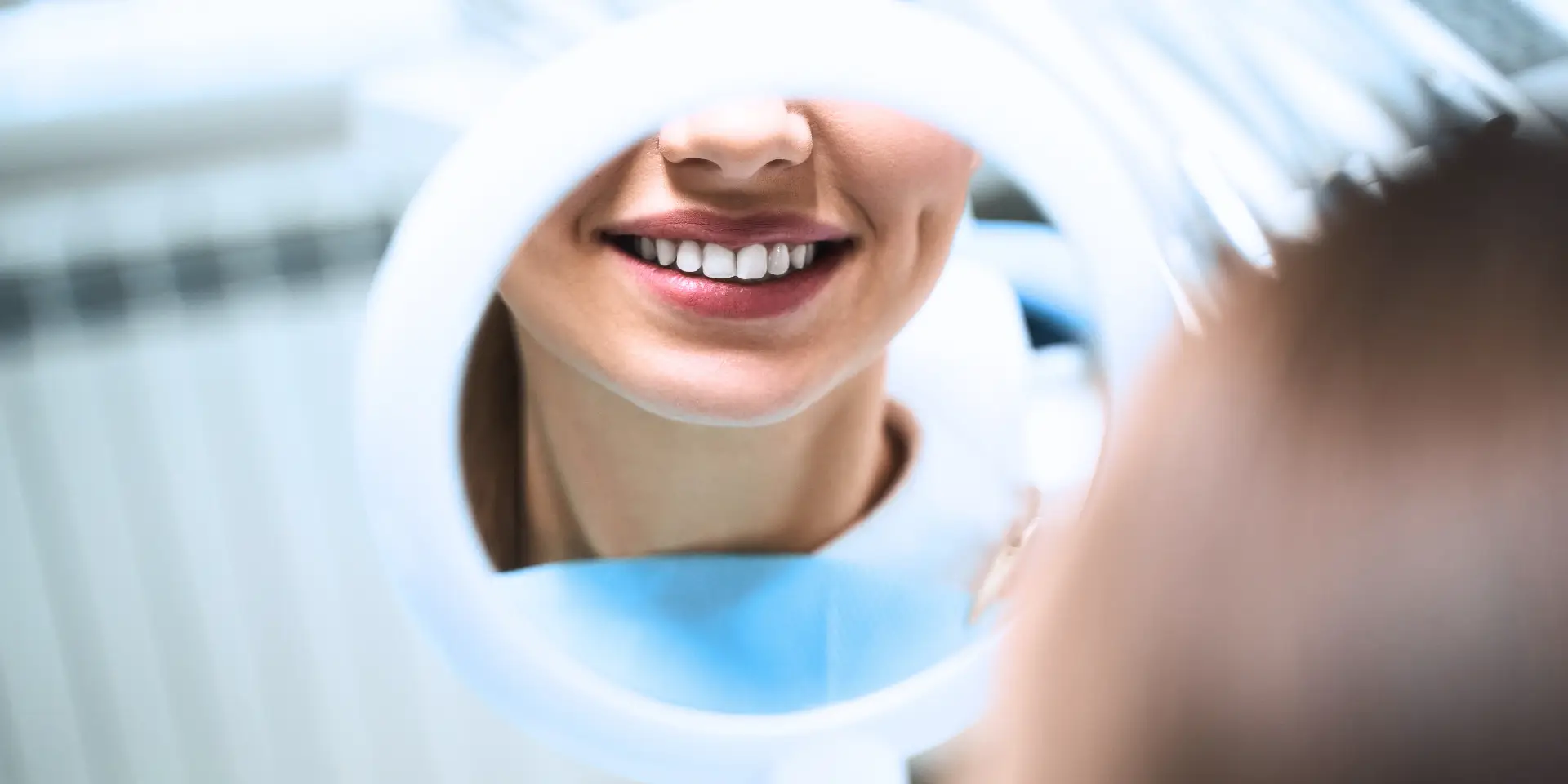 BLOG Mujer sonriendo al espejo en nuestra clínica dental de Valladolid