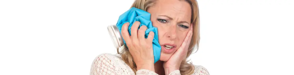 Mujer aplicando frío en la mejilla para aliviar el dolor de muela antes de ir al dentista